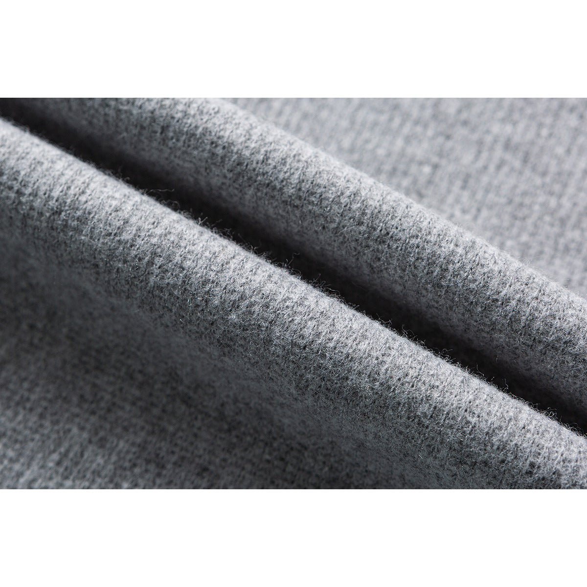 Close-up of light gray knit fabric folded to show its textured surface.