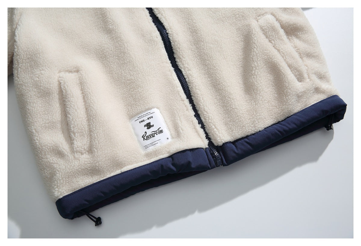 Cropped front of a cream sherpa jacket with two pockets, a dark zipper, navy hem trim, and sewn label.