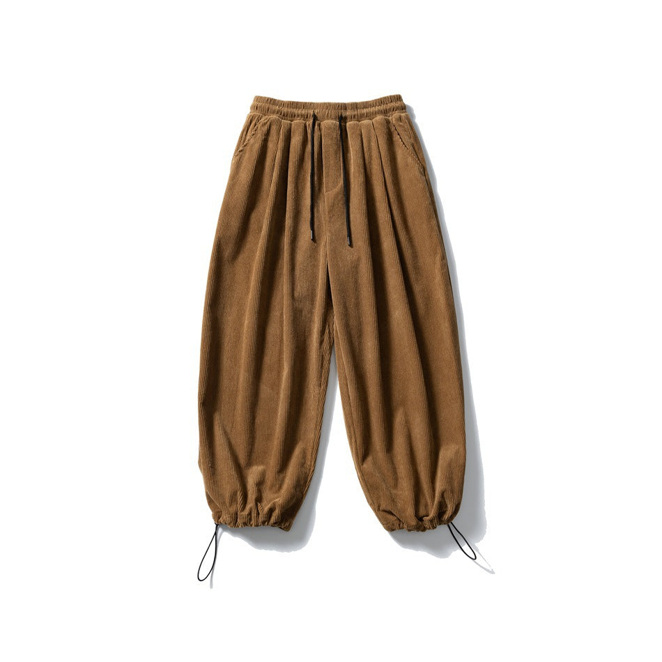 Front view of brown corduroy pants with a gathered elastic waist, black drawstrings, and elastic drawstring cuffs.