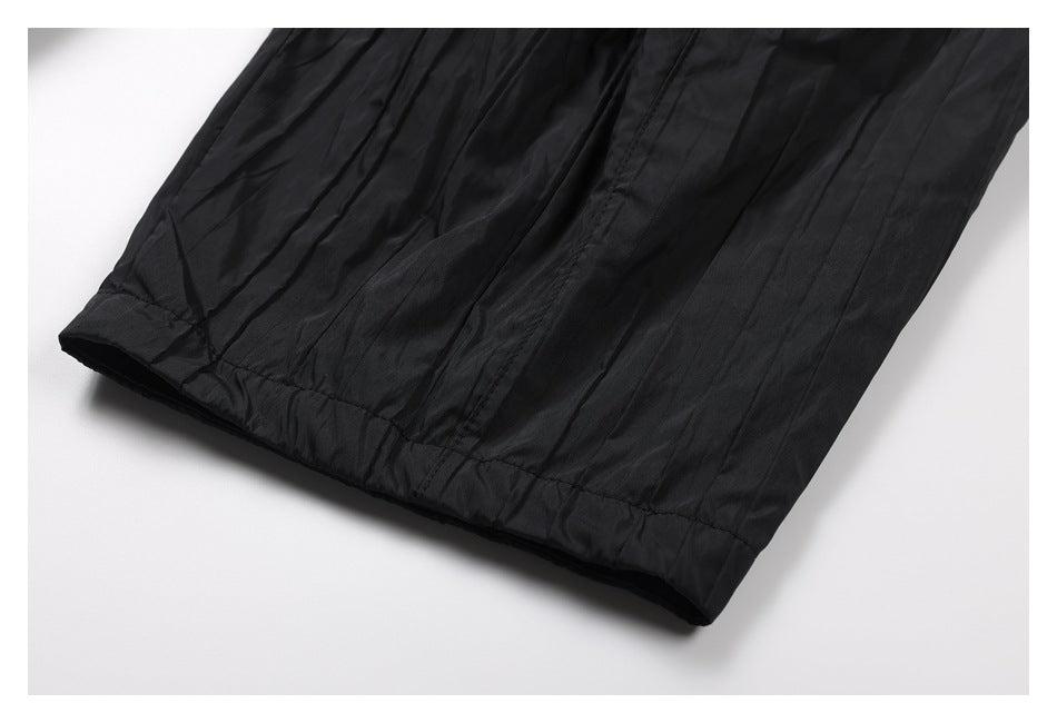 Close-up of the black trouser leg and stitched hem laid flat on a white background.