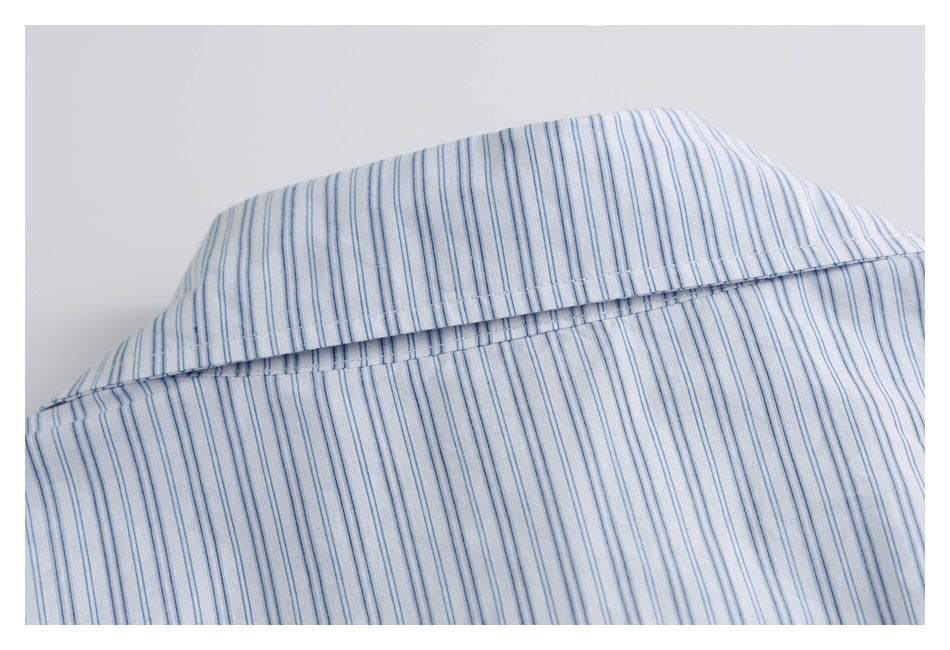 Close-up of the pointed collar on a white shirt with thin blue stripes.