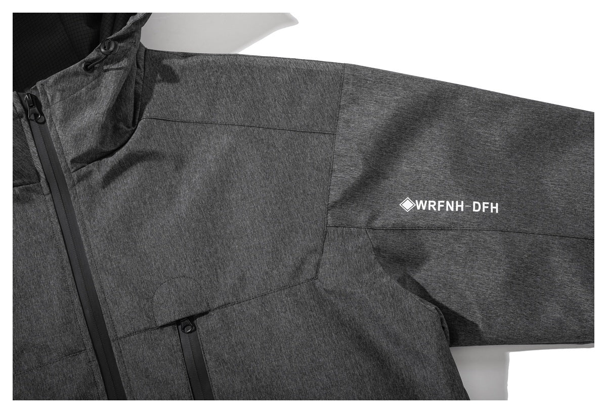 Close-up of the charcoal jacket's sleeve and front, showing a white geometric code print and zippered pocket.
