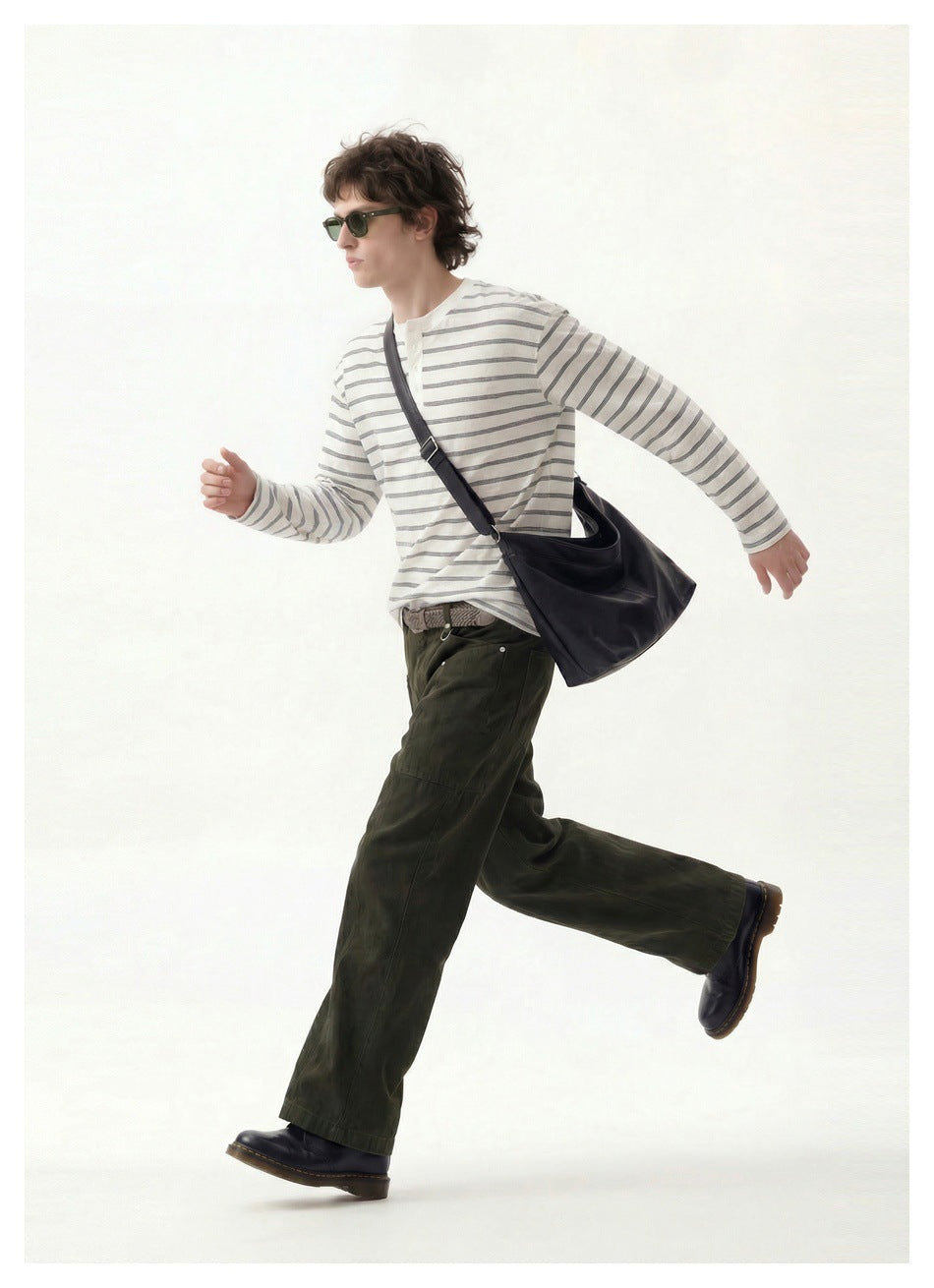 Model wearing a striped white long-sleeve Henley, shown in a side-facing pose with a shoulder bag.