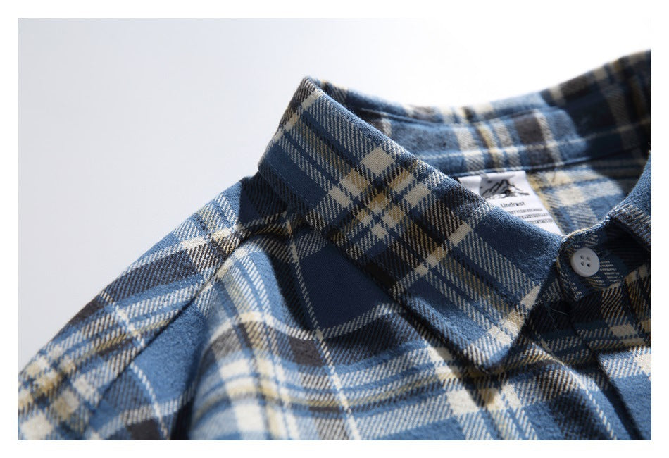 Close-up of a blue plaid button-up shirt showing its pointed collar, white button and inner neck label.