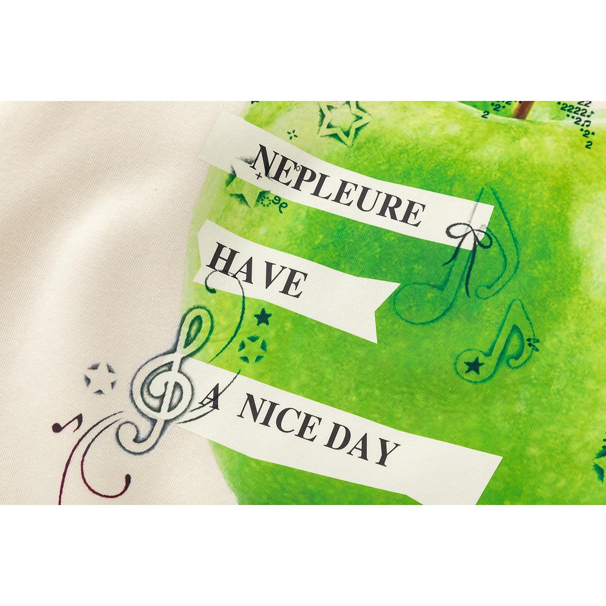 Close-up of a green apple graphic with music notes and English text printed on cream fabric.