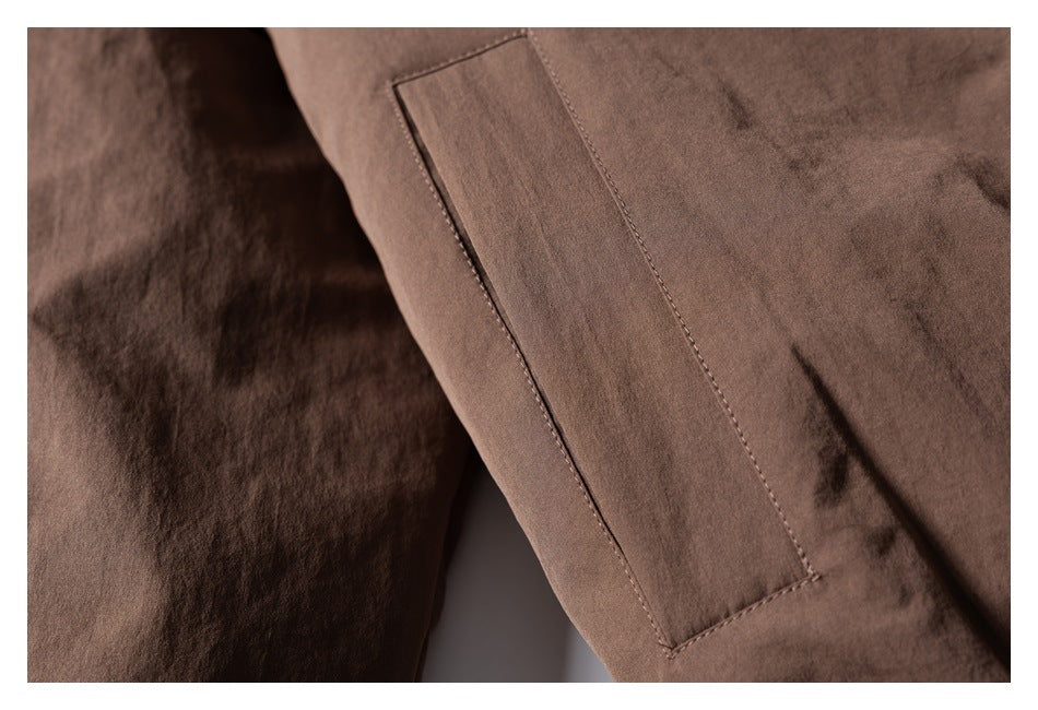 Close-up of a long, narrow welt pocket on a brown jacket.