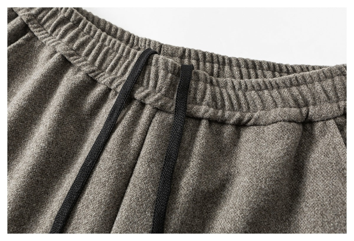 Close-up of gray pants with a gathered elastic waistband and two black drawstrings.