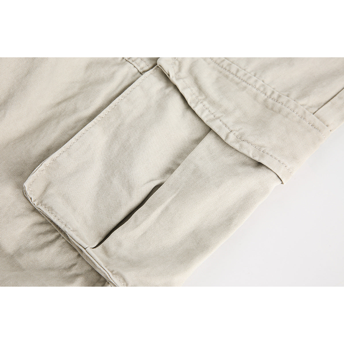 Close-up of a beige cargo pant leg and its large flap pocket.