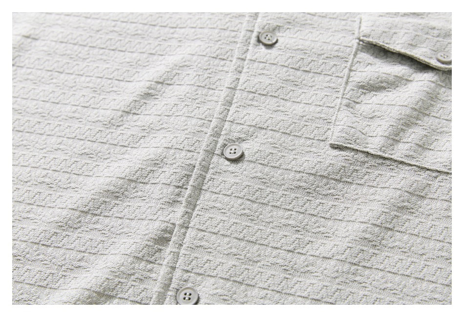 Close-up of the light gray shirt's button front and patterned fabric.