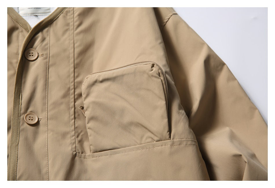Close-up of a tan jacket showing a large chest pocket, front buttons, and sleeve.