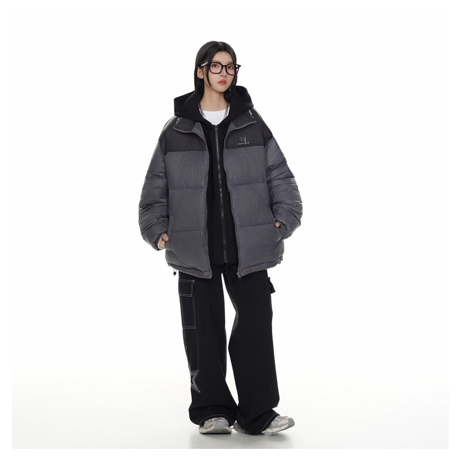 Model wearing a charcoal-gray puffer jacket with black shoulders and hood, layered over a black hoodie.