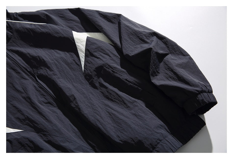 Close-up of the windbreaker’s navy sleeve, elastic cuff, and angular white panel.