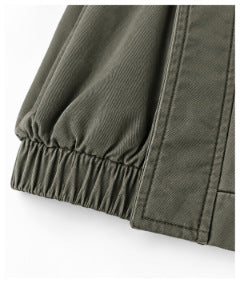 Close-up of an olive-gray garment sleeve with a gathered elastic cuff beside a stitched seam.