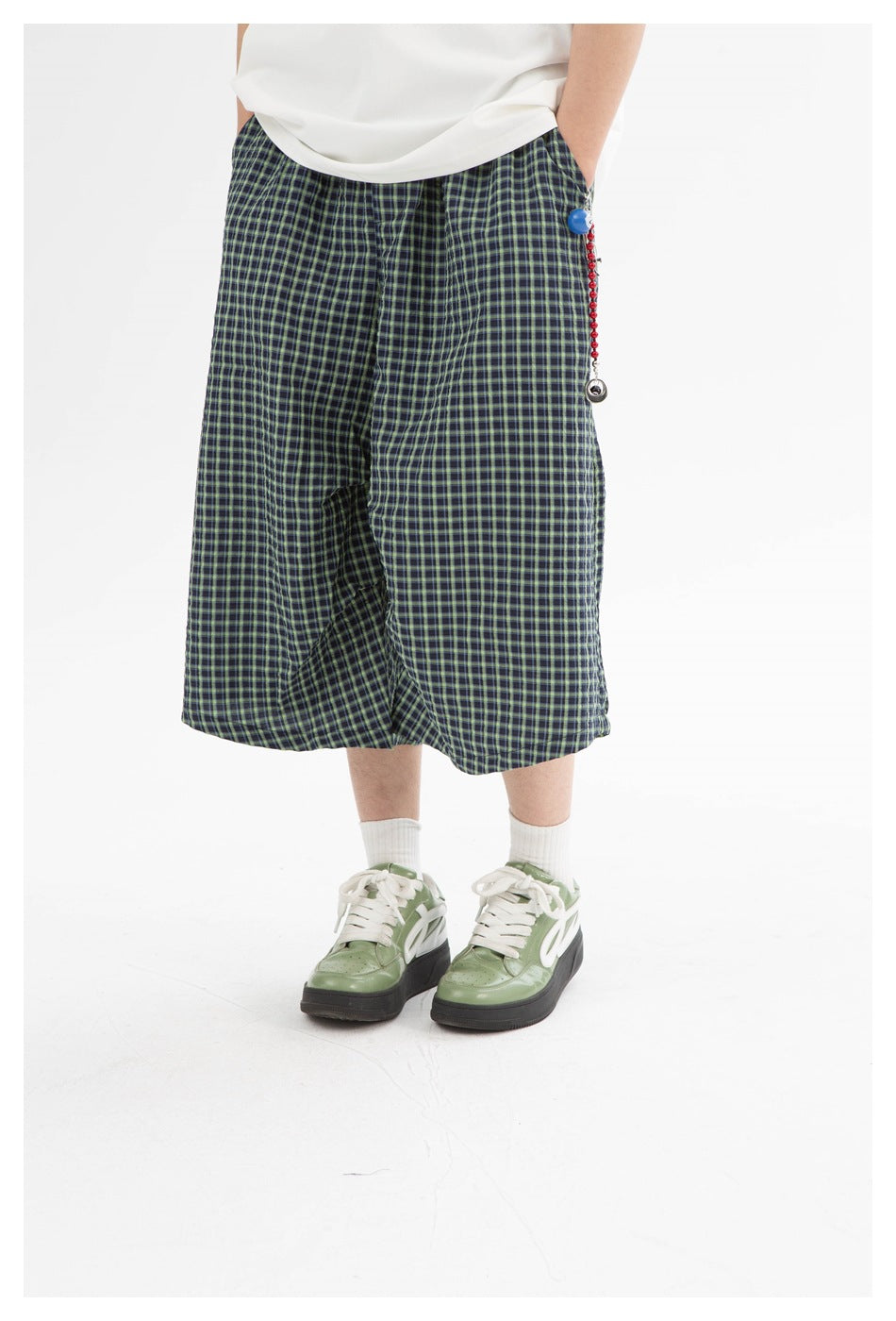 Close view of navy and green plaid wide-leg shorts worn with white socks and green sneakers