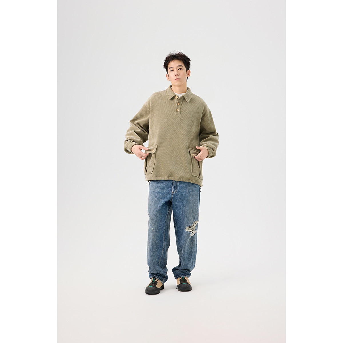 Front view of a model wearing an oversized olive collared pullover with a three-button placket and flap pockets.