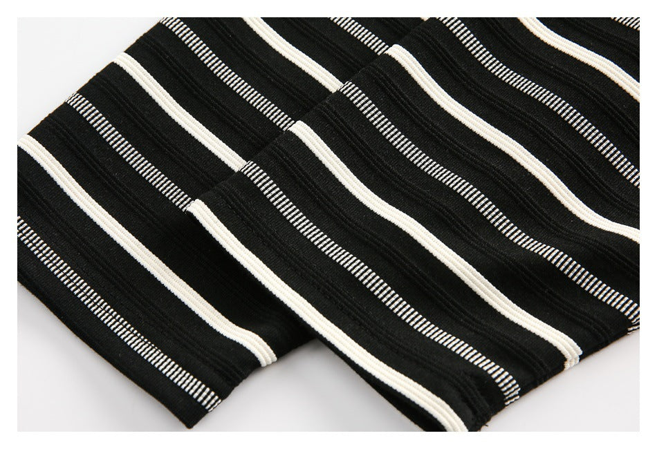 Close-up of folded black fabric with cream and narrow white stripes.