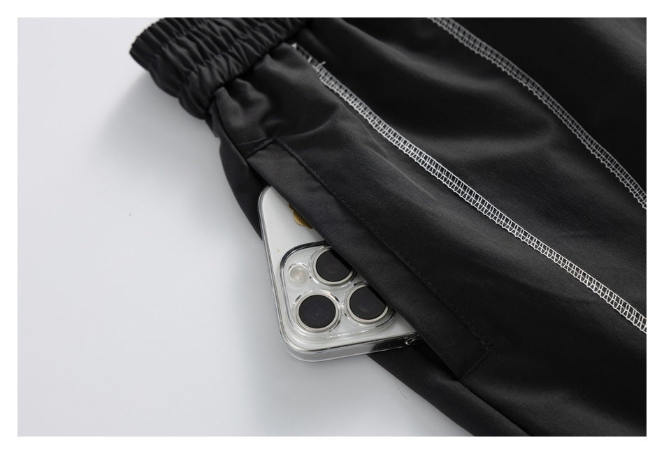 Close-up of a black pants pocket holding a smartphone, with white overlock stitching visible nearby.