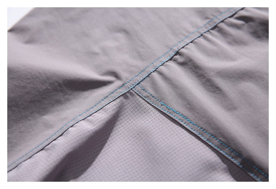 Close-up of gray garment panels with blue stitching and a light gray mesh inset.