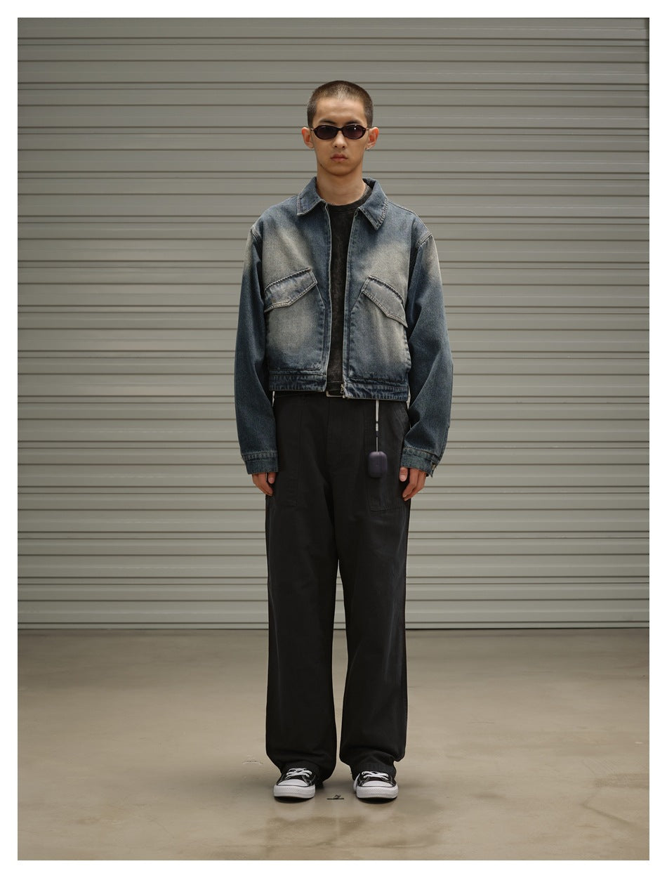 Model wearing cropped washed blue denim zip jacket with black pants and sneakers in front of a gray shutter