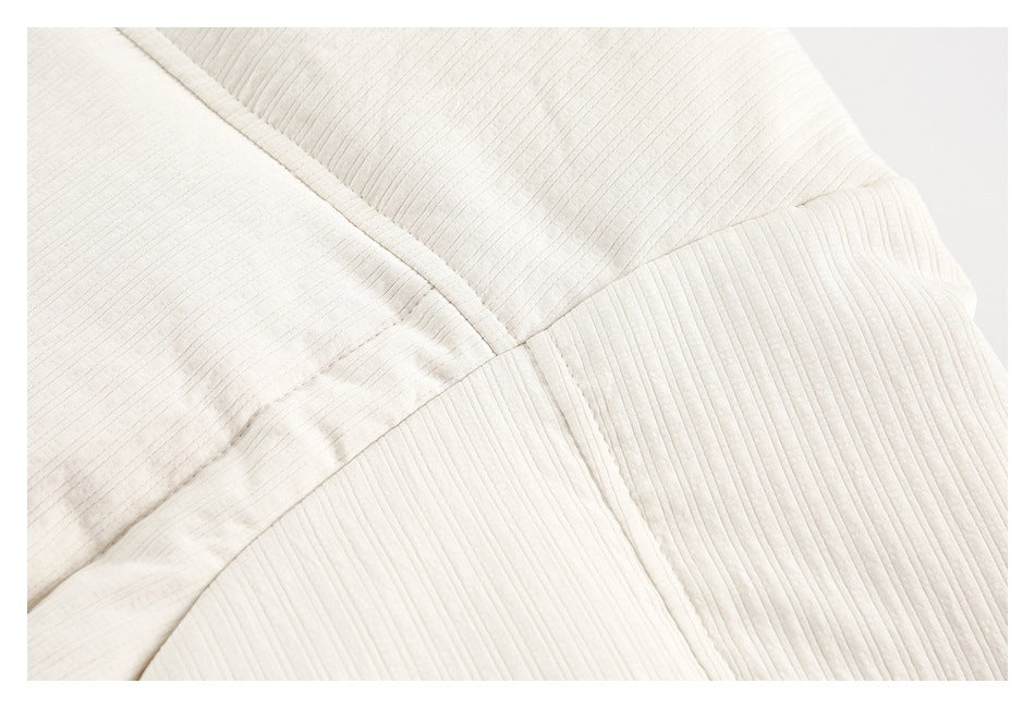 Close-up of ivory garment fabric showing a diagonal seam and fine vertical ribbing.