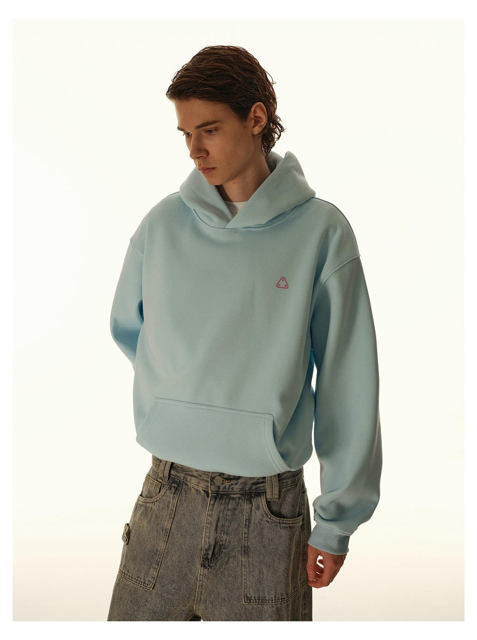Model wearing a sky blue hoodie with a front kangaroo pocket and small pink triangle chest logo, styled with washed jeans