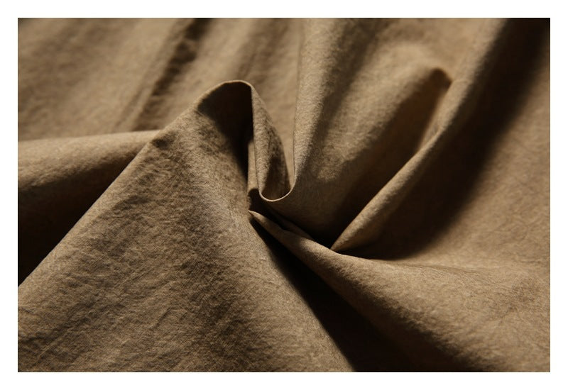 Close-up of brown fabric gathered into folds, showing its surface texture.