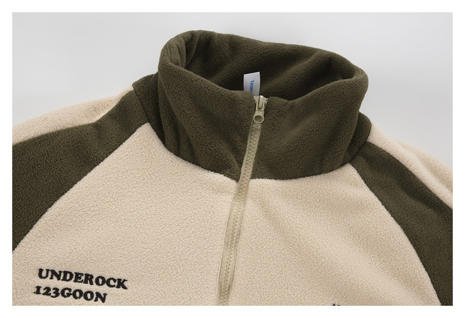 Close-up of the cream-and-olive jacket's high collar and front zipper, with black text printed on the chest.