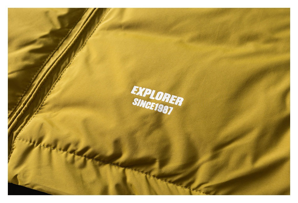 Mustard yellow jacket close-up with white garment text reading “EXPLORER SINCE 1987.”
