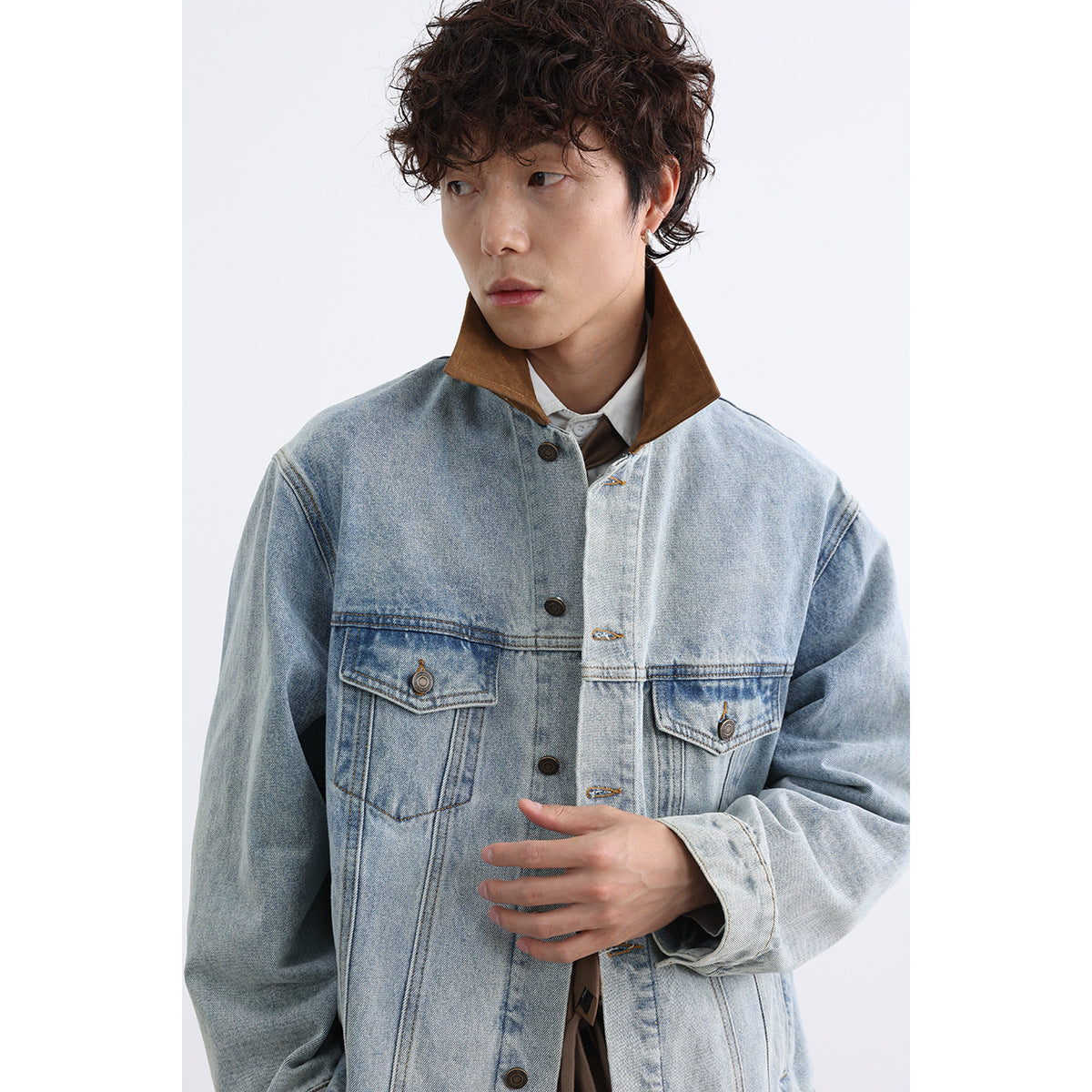 Close view of a model wearing a light-wash denim jacket with a contrasting brown collar and two flap chest pockets.