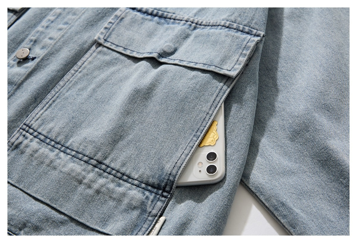 Close-up of a light blue denim garment's large pocket, with a phone tucked inside.