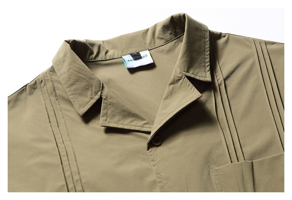 Close-up of an olive-khaki shirt collar, lapels, button, stitched shoulder pleats and inner neck label.