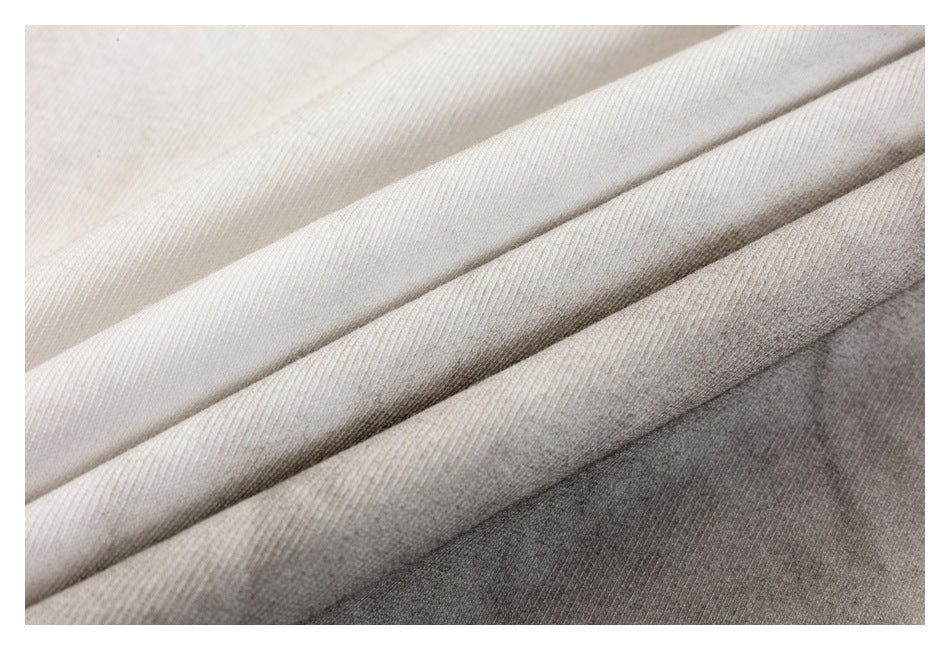 Close-up of layered fabric in shades ranging from ivory to medium gray, showing its surface texture.