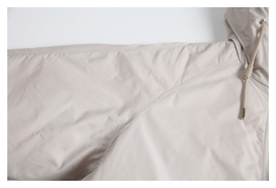 Close-up of a light beige jacket panel with curved seam and adjustable drawcord.