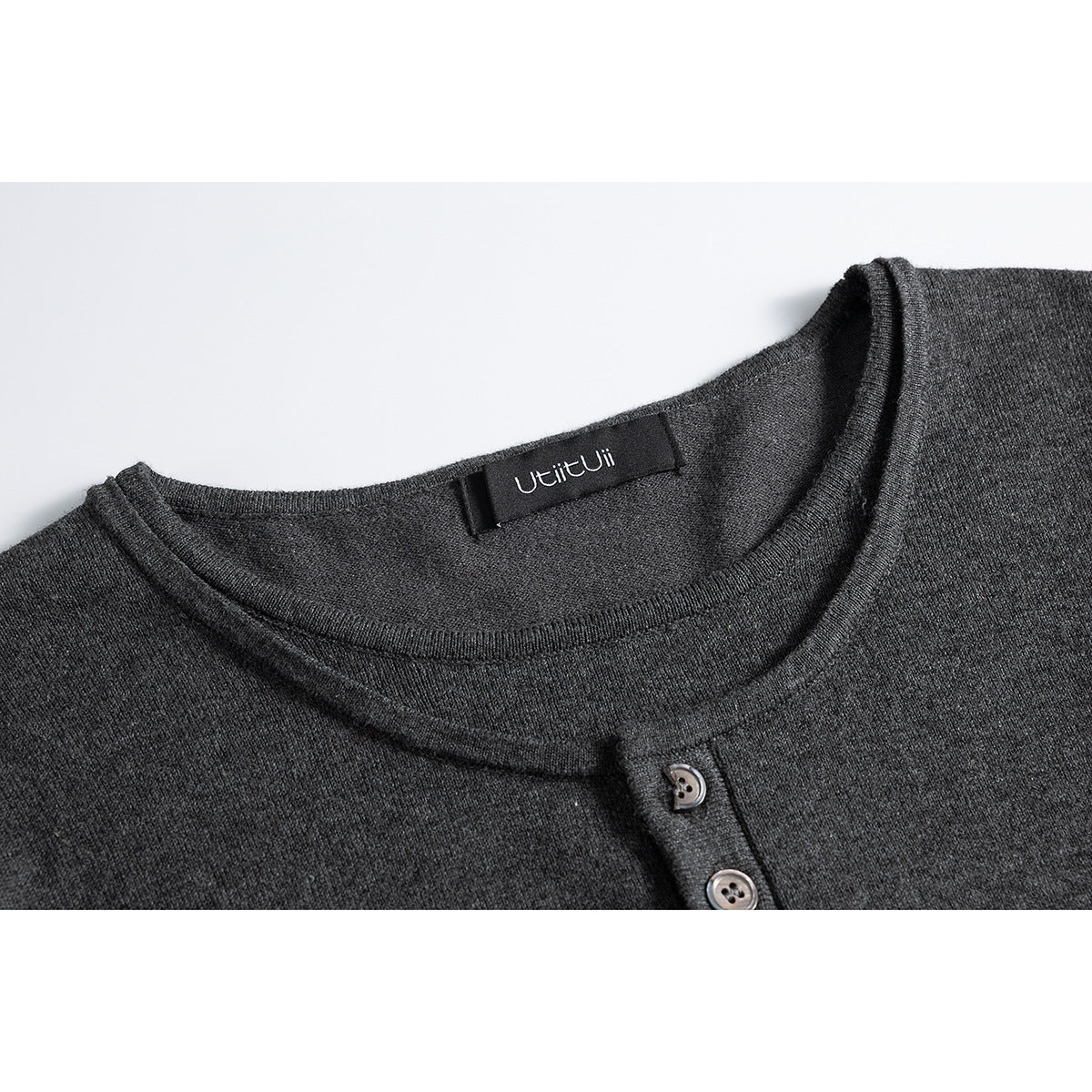 Close-up of a charcoal gray shirt’s crew neckline, sewn label and short button placket.