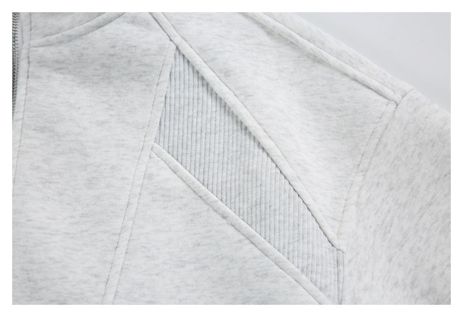Close-up of a light gray marled jacket sleeve and shoulder, with a ribbed inset panel and curved seam piping.