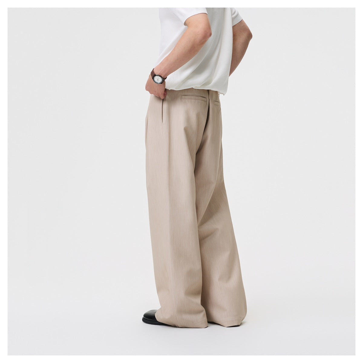 Cropped model wearing beige wide-leg trousers, shown from the back with two welt pockets.