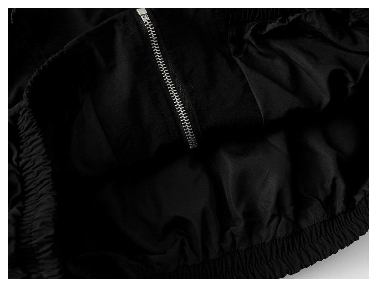 Close-up of black garment with a silver zipper and gathered elastic trim.