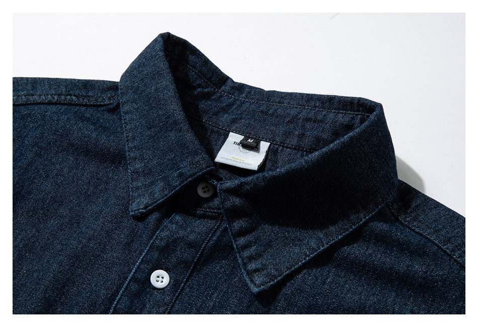 Close-up of a dark indigo button-up shirt collar and placket with a sewn-in neck label.