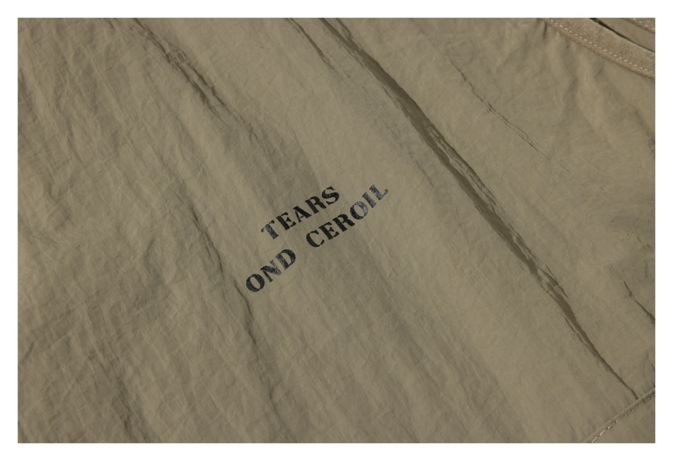 Close-up of wrinkled khaki fabric with black stenciled lettering.