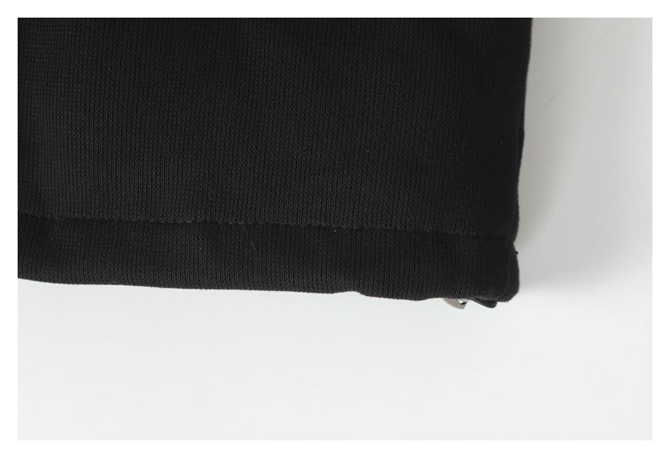 Close-up of the hem of a black garment against a white background.