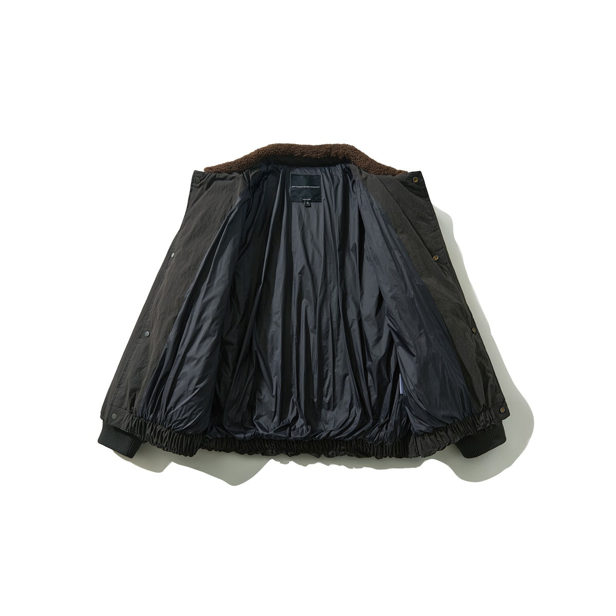 Open dark charcoal jacket laid flat, showing shiny black lining, brown fleece collar, snap front and ribbed cuffs.