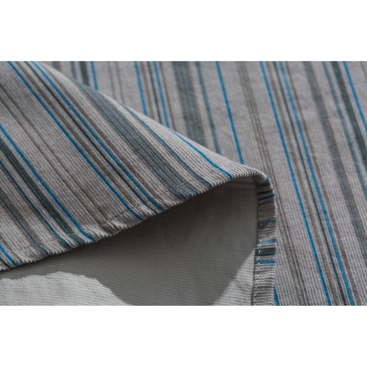 Close-up of gray fabric with thin blue stripes, showing a folded edge and stitching.