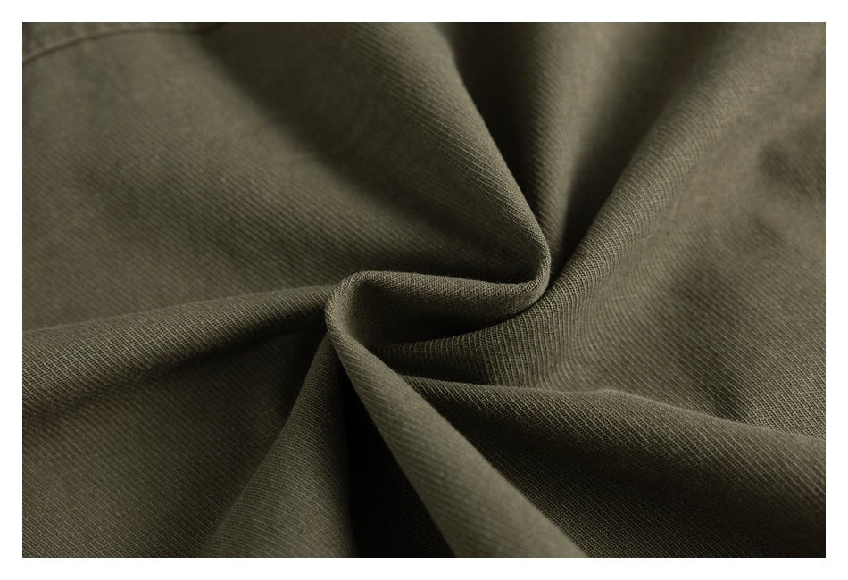 Close-up of olive-green fabric gathered into folds, showing its fine surface texture.