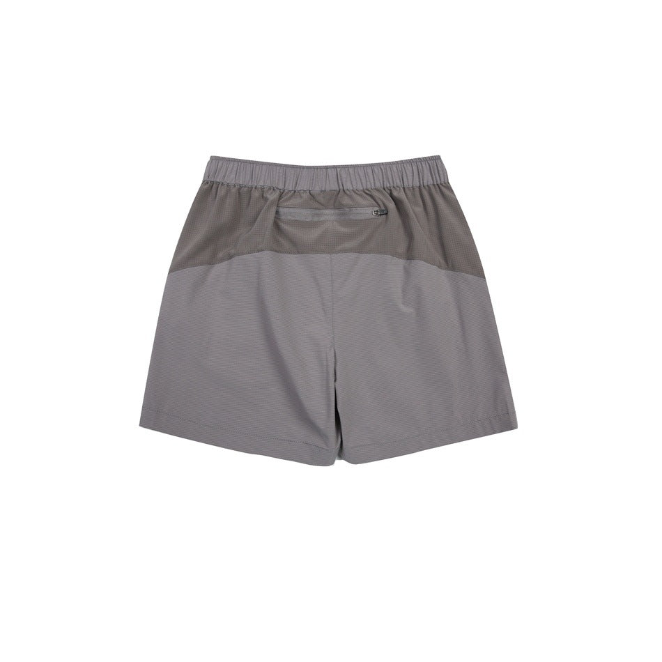 Rear view of gray athletic shorts with an elastic waistband, darker upper panel, and zippered back pocket.