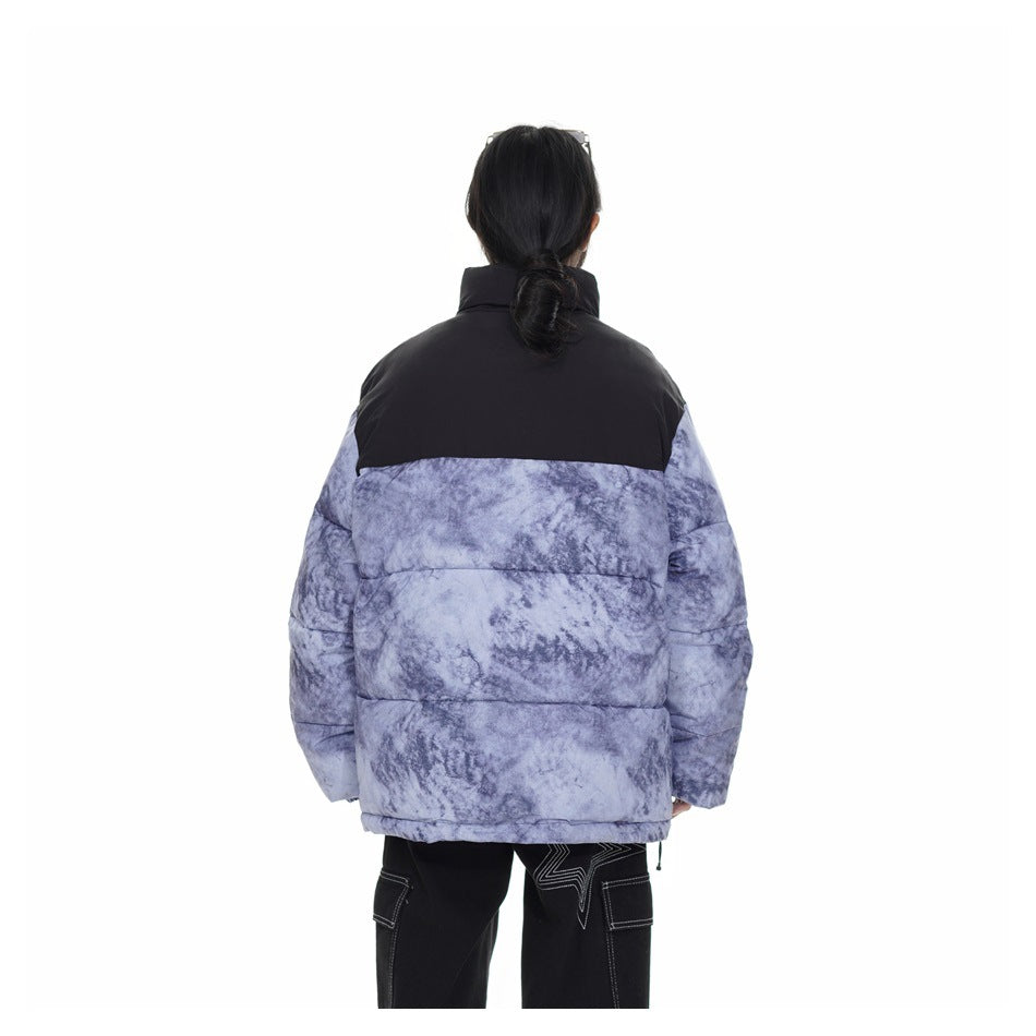 Rear view of a model wearing a lavender-gray marbled puffer jacket with a black upper back panel.