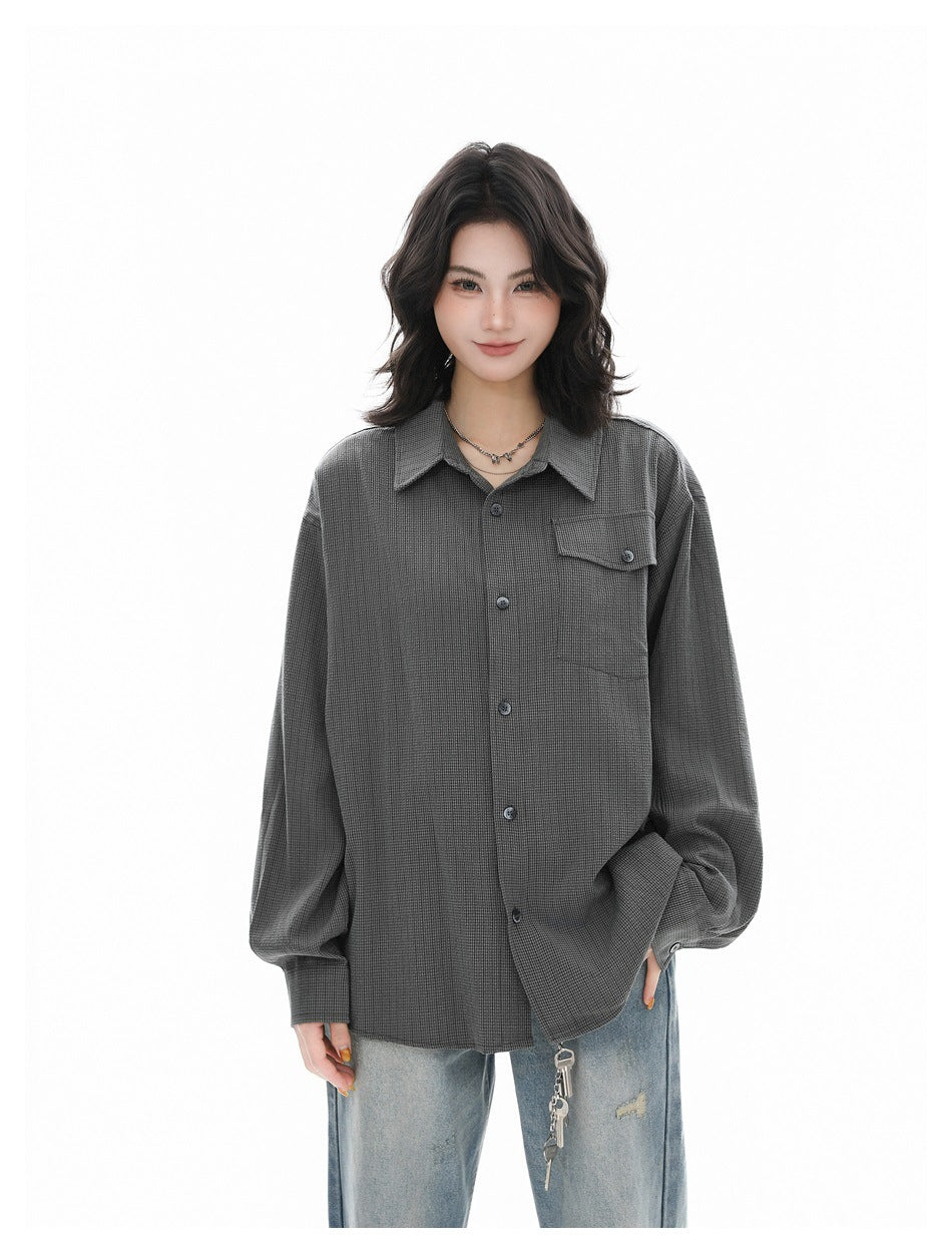Front view of a person wearing an oversized charcoal gray button-up shirt with a buttoned chest pocket and blue jeans.