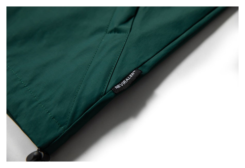 Close-up of a dark teal garment hem with a small woven label and drawcord toggle.