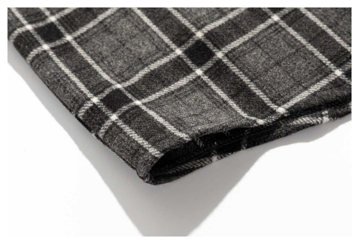 Close-up of the folded hem edge of a dark gray and black plaid garment.