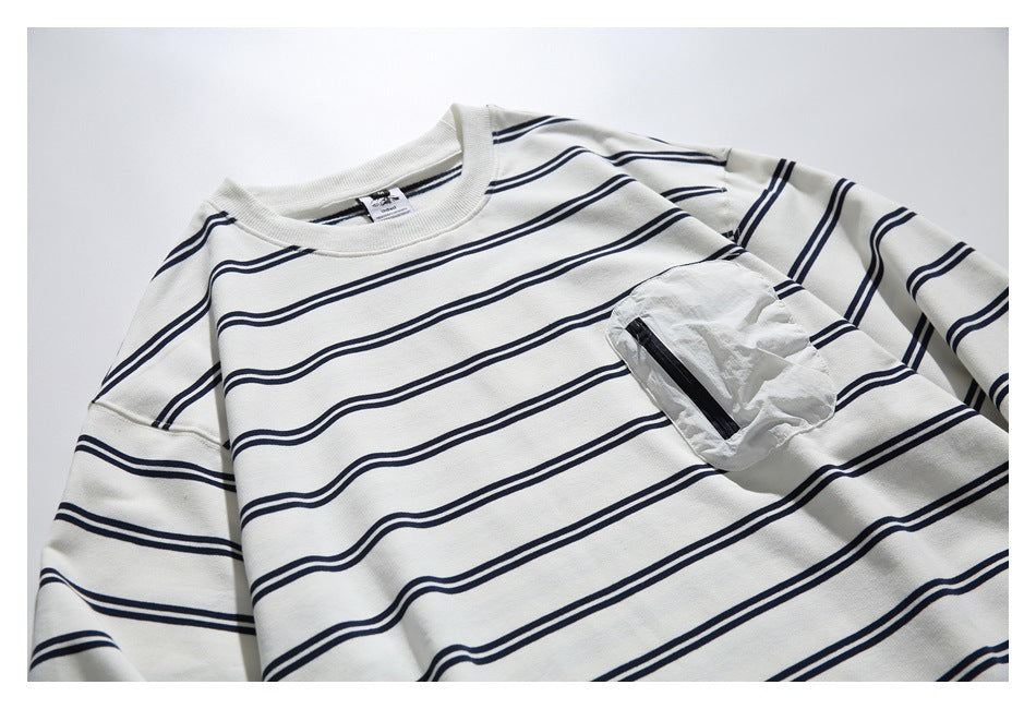 Close-up of an ivory long-sleeve shirt with navy stripes and a crinkled chest pocket with a black zipper.