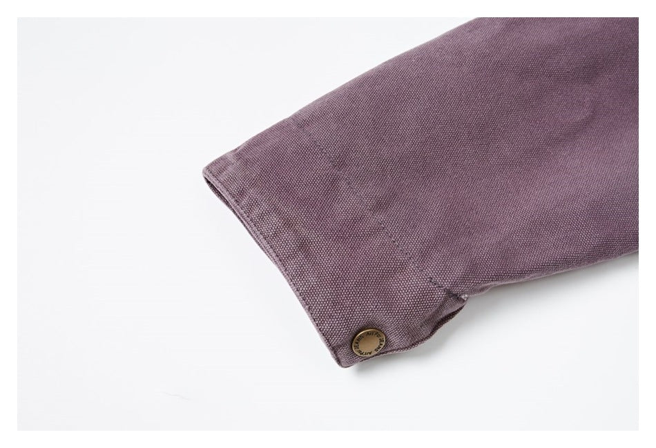 Close-up of a muted purple garment cuff with a small round metal button.
